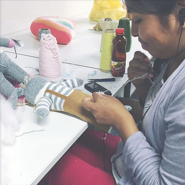 A woman sewing a stuffed doll.